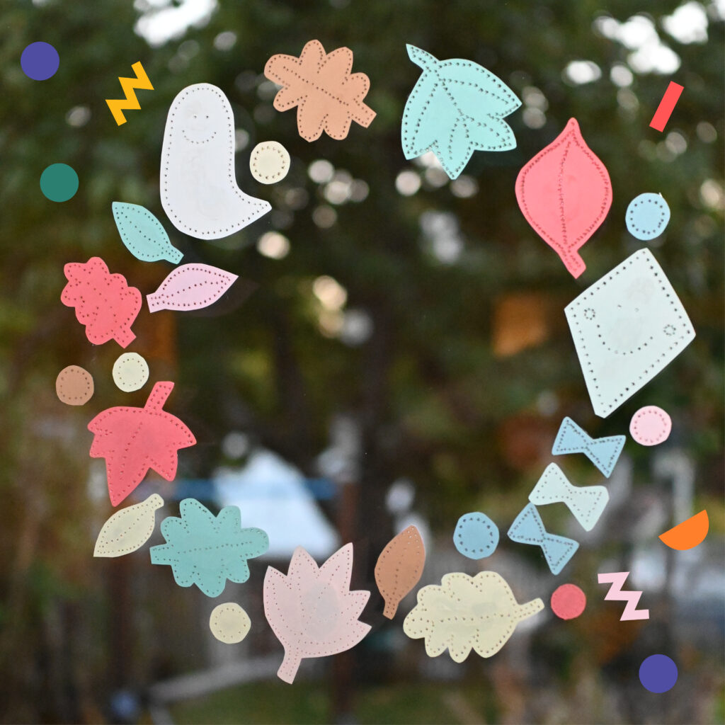 Buntes Herbst-Fensterbild aus geprickelten Blättern und Herbstmotiven